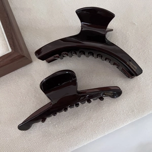 Deep brown acetate hair claw set with gold Barrette La France text on glossy surface