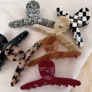 Macro shot of assorted acetate French hair claws with elegant patterns on white fabric