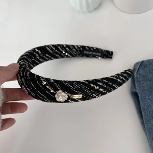 Detail showing tweed texture and camellia flower on a padded headband for women