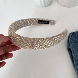 Detail of tweed headband with white camellia flower, pearl inlay and metal logo tag