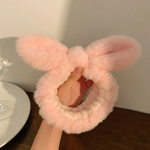 Close-up of soft pink plush rabbit ear headband with a fluffy bow for face washing