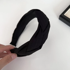 Vue détaillée du serre-tête tressé noir avec texture de tissu à carreaux fins