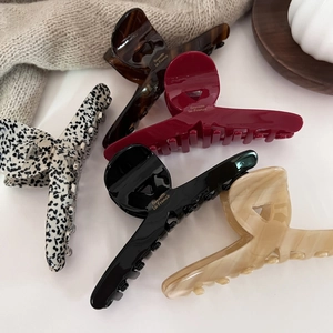 Five large acetate hair claws in tortoise shell and marble patterns with gold lettering