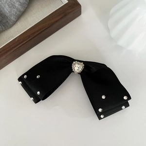 Detailed view of the black satin bow hair clip with heart rhinestone and crystal accents