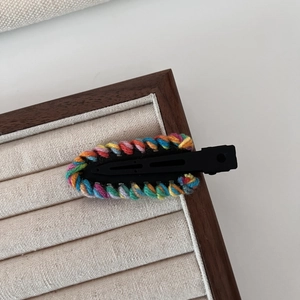 Close-up of a colorful hand-woven yarn crochet hair clip on a wooden display stand