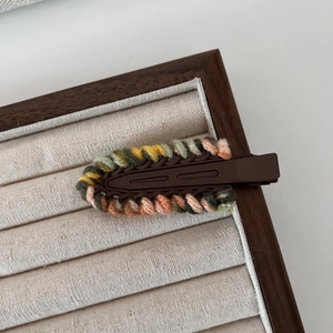 Detailed macro view of woven yarn hair clip featuring vibrant multi-color wool texture
