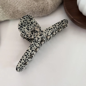 Detail of dalmatian print acetate hair claw clip on a warm aesthetic background