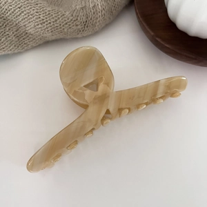 Macro detail of large acetate hair claw clip with beige marble texture on a white surface
