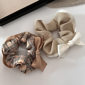 Detailed view of khaki plaid and waffle texture bow scrunchies on a soft white surface