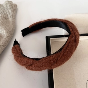 Gros plan d'un serre-tête en maille torsadée marron avec une texture pelucheuse douce