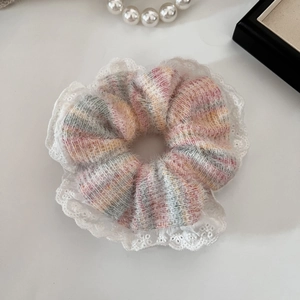 Dettaglio di un elastico per capelli in maglia di peluche con strisce colorate e pizzo
