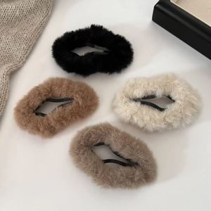 Close-up of four fluffy faux fur hair clips in black, beige, and brown colors for winter