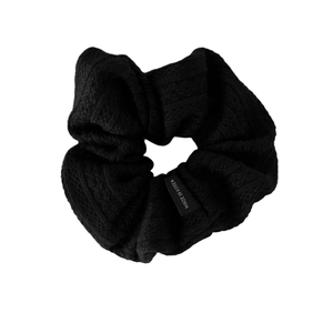 Black knitted scrunchie with soft ribbed texture and Made in Korea label on white background