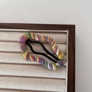 Detalle de pinza para el pelo con forma de nube envuelta en lana de colores en soporte