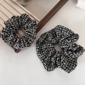 Close-up of black and white houndstooth tweed scrunchies on a beige jewelry tray