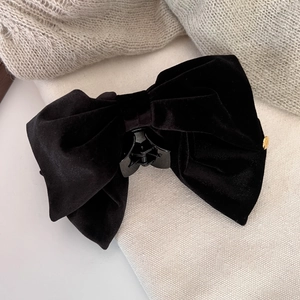 Close-up of elegant black velvet bow hair claw with a small gold metal logo detail