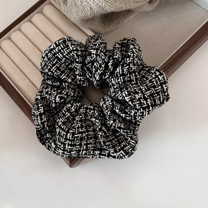 Detail of classic black and white tweed scrunchie on a premium jewelry display tray