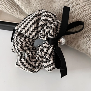 Elegant tweed scrunchie with silk bow and pearl pendant on a beige sweater