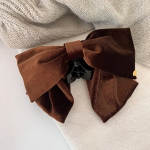 Detailed macro view of dark coffee velvet bow hair claw clip with golden metal emblem