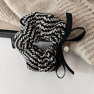 Detail of tweed scrunchie with black bow, pearl pendant and elegant woven texture