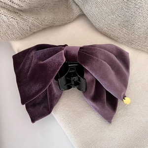 Close-up of a deep purple velvet bow hair claw clip with a small gold metal charm detail