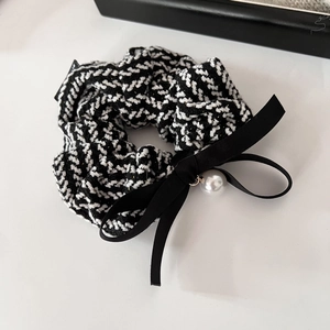 Detail of tweed scrunchie with velvet bow and elegant faux pearl charm on white background