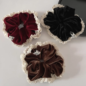 Detailed close-up of three velvet lace scrunchies in burgundy, black and brown colors