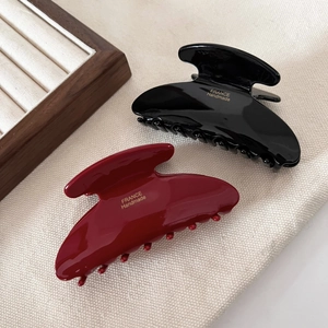 Close-up of black and burgundy acetate hair claws with France Handmade gold lettering