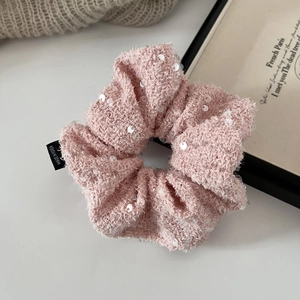 Detailed view of pink sequin tweed scrunchie with soft knit texture on white background