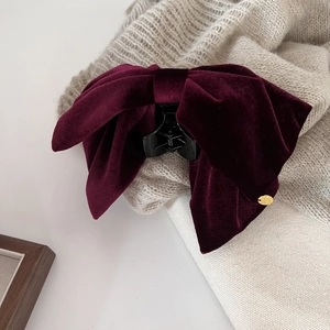 Detailed macro view of a burgundy velvet bow hair claw clip with golden metal charm