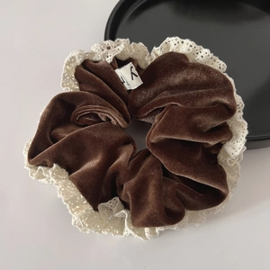 Detail of vintage brown velvet scrunchie with white lace edges and a small woven label