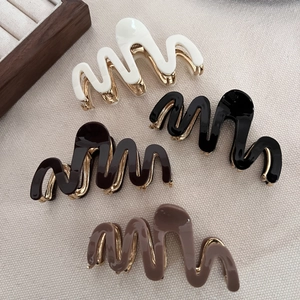Set of four wavy acetate hair claws in black, white, and brown with gold metal springs
