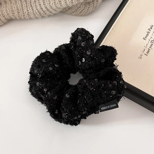 Detailed macro view of black sequin tweed scrunchie with Made in Korea woven label