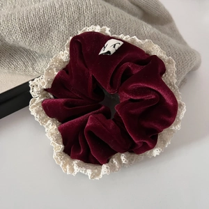 Detail of burgundy velvet scrunchie featuring cream lace trim and elegant soft texture