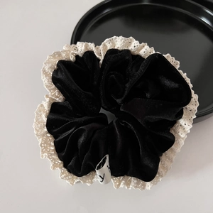 Detail of black velvet scrunchie featuring vintage cream lace edge and brand tag