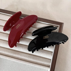 Detail of red and black acetate hair claws with gold France Handmade logo in a tray