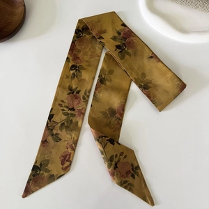 Detail of vintage French floral silk hair scarf with rose pattern on a warm bronze surface