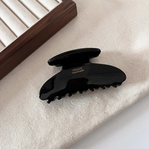 Detailed close-up of glossy black hair claw with gold France Handmade logo engraving
