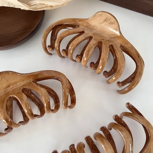 Three large French-style wood grain shark clips for elegant hair styling on white desk