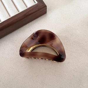 Elegant crescent-shaped tortoiseshell acetate hair claw clip with golden metal teeth
