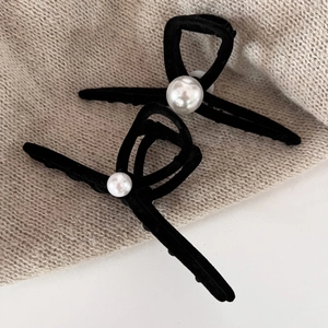 Close-up of black velvet bow hair clips with elegant pearls on textured background