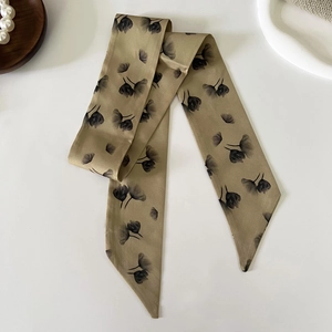 Detail of elegant silk twilly scarf with black tulip pattern and champagne gold finish