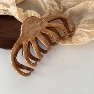 Detailed view of brown oil-paint texture hair claw clip on rustic wood background