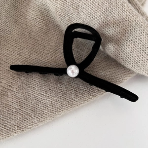 Close-up of elegant black velvet bow hair claw clip with a single white pearl accent