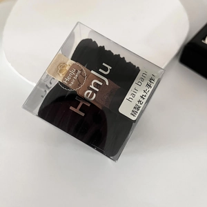 Detail view of durable black seamless elastic hair bands in a clear square gift box