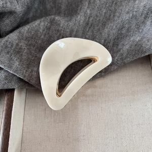 Detailed close-up of cream crescent hair claw with elegant gold metallic inner lining