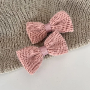 Close-up of pink knitted bow hair clips showing soft yarn texture and satin ribbon detail