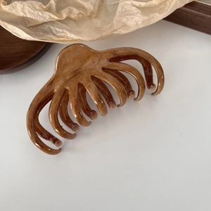 Macro shot of large amber octopus hair claw with glossy wood grain texture for French styling