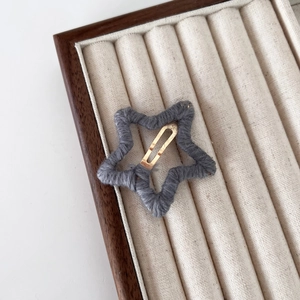 Barrette étoile tricotée grise avec clip en métal doré sur un plateau d'exposition