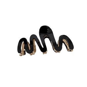Elegant wavy hair claw clip in black acetate with a gold metal base on white background